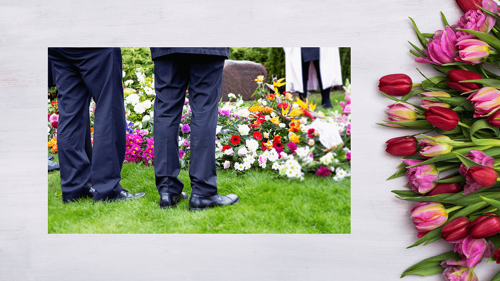 people standing near grave with flowers