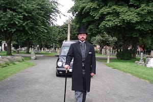 Funeral director walking ahead of hearse