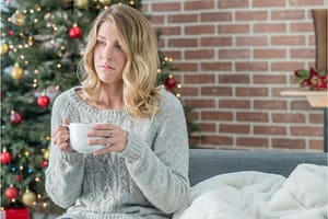 Lady looking sad in front of a Christmas tree