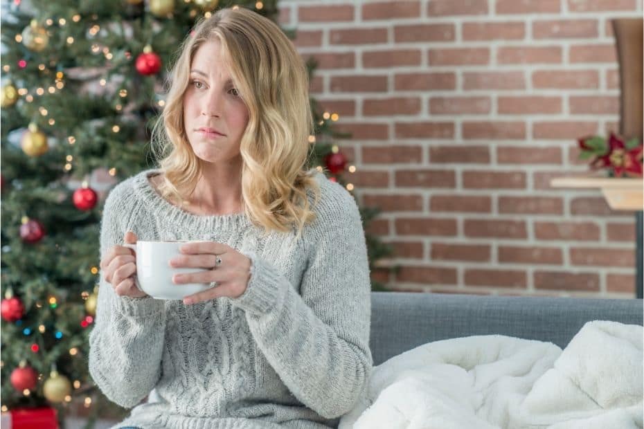 Lady looking sad in front of a Christmas tree