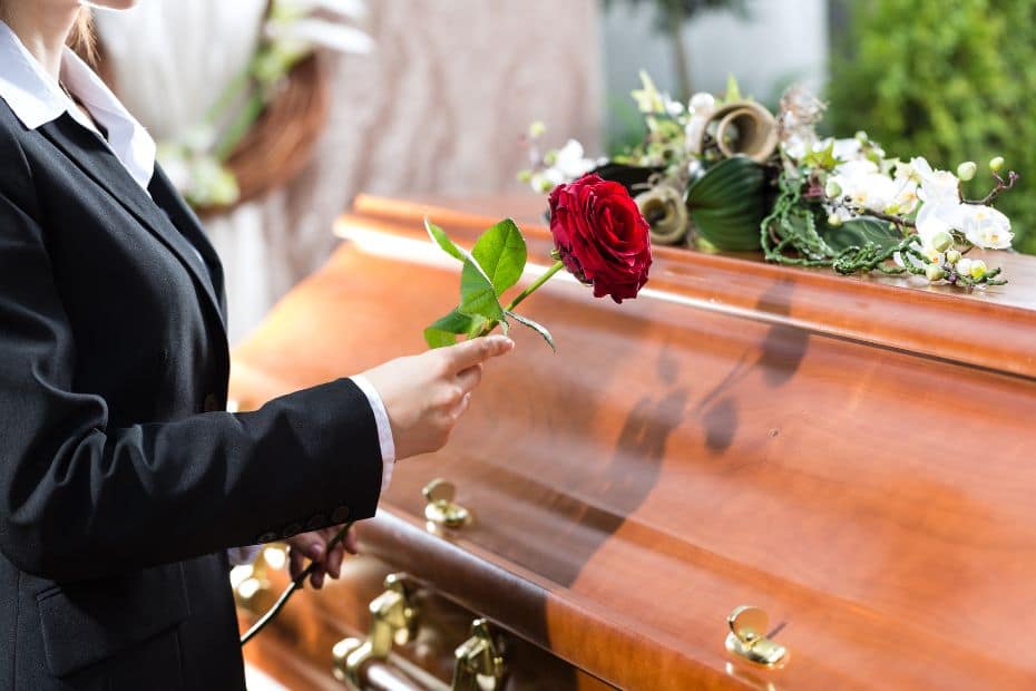 Person placing a rose on a coffin